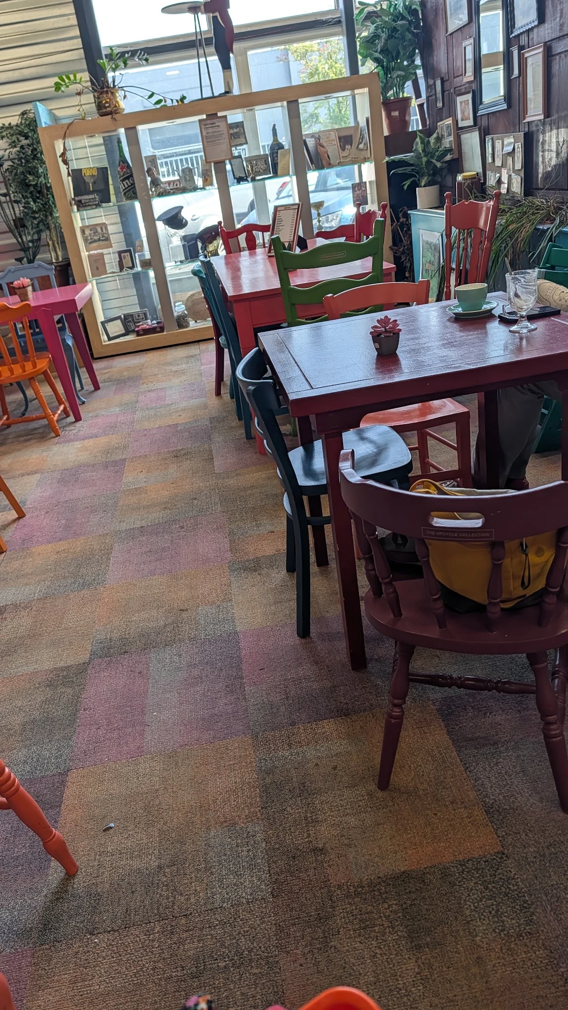 Winkelvloer met verschillende tafels en stoelen, waaronder een rode tafel met zwarte stoelen en een ronde rode tafel met gele