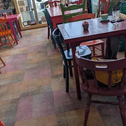 Winkelvloer met verschillende tafels en stoelen, waaronder een rode tafel met zwarte stoelen en een ronde rode tafel met gele