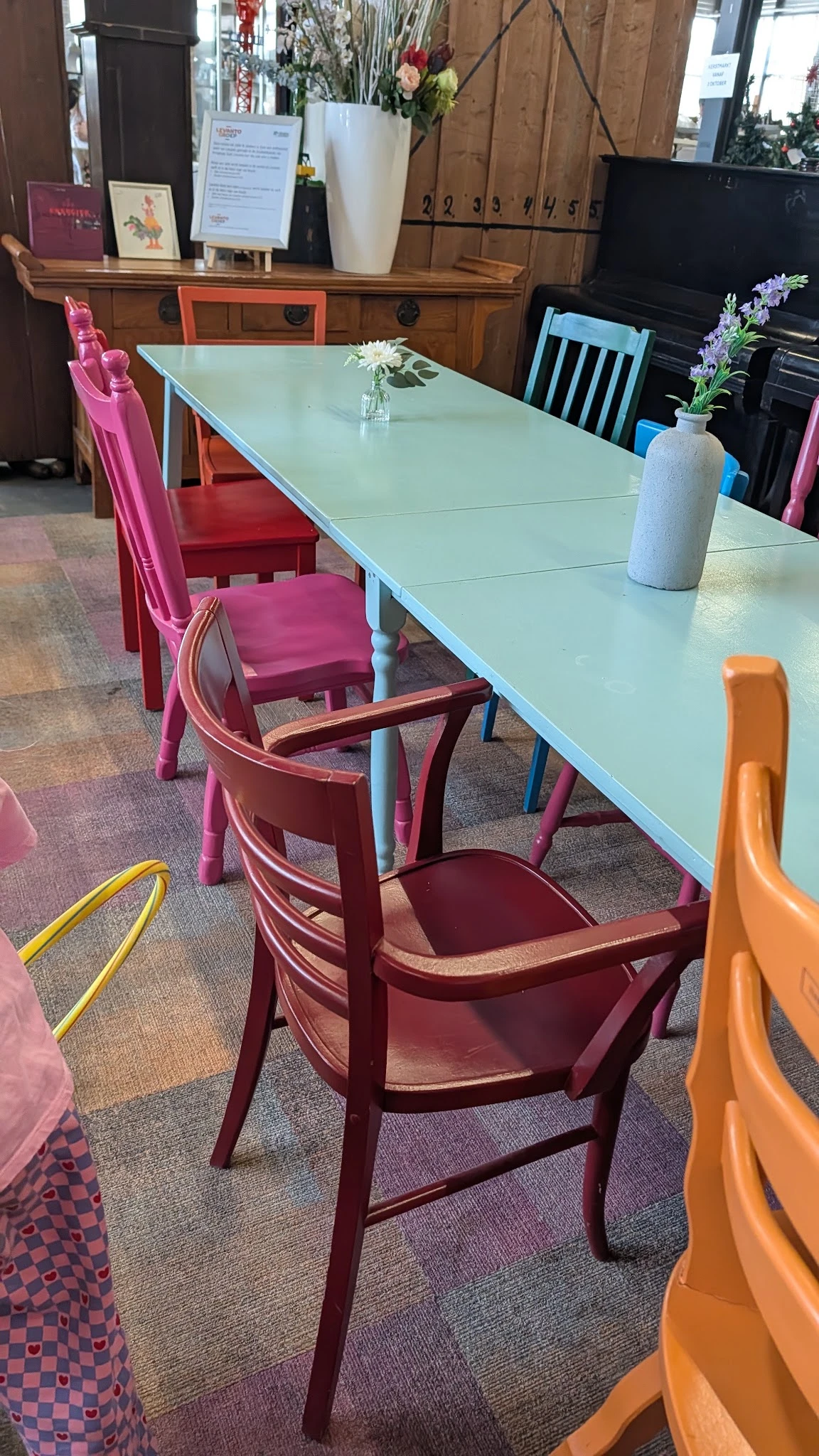 Eettafel met lichtblauwe blad en gekleurde stoelen in roze, rood en oranje in de winkelruimte