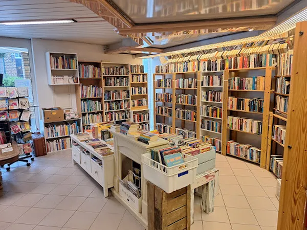 Overzicht van boekenwinkel met boeken in kasten langs de wanden en op tafels in het midden