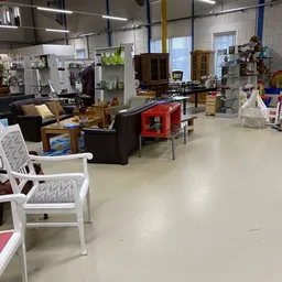 Winkelvloer met diverse meubels: zwarte fauteuils, rode tafel, witte stoelen en houten kasten op de achtergrond
