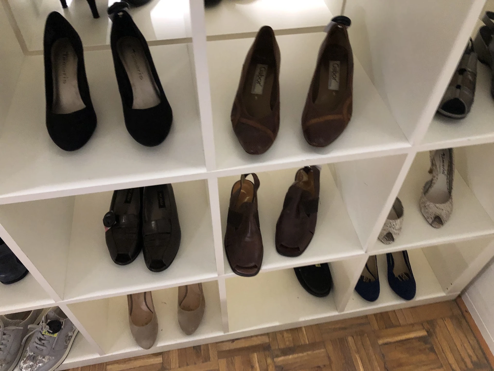 Witte stellage met diverse tweedehands damesschoenen in zwart, bruin en grijs
