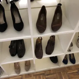 Witte stellage met diverse tweedehands damesschoenen in zwart, bruin en grijs