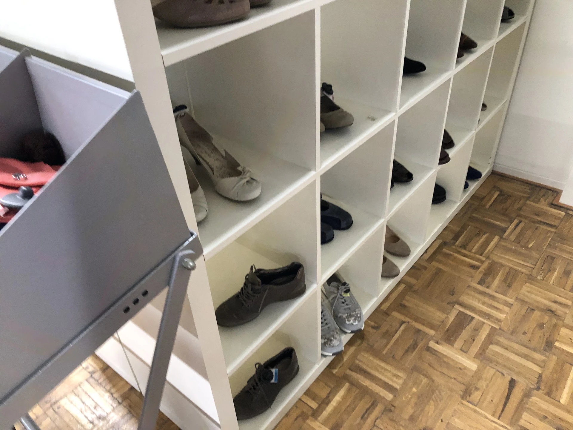 Wit schoenenkast met meerdere vakken vol met tweedehands schoenen in verschillende kleuren en stijlen