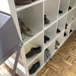 Wit schoenenkast met meerdere vakken vol met tweedehands schoenen in verschillende kleuren en stijlen