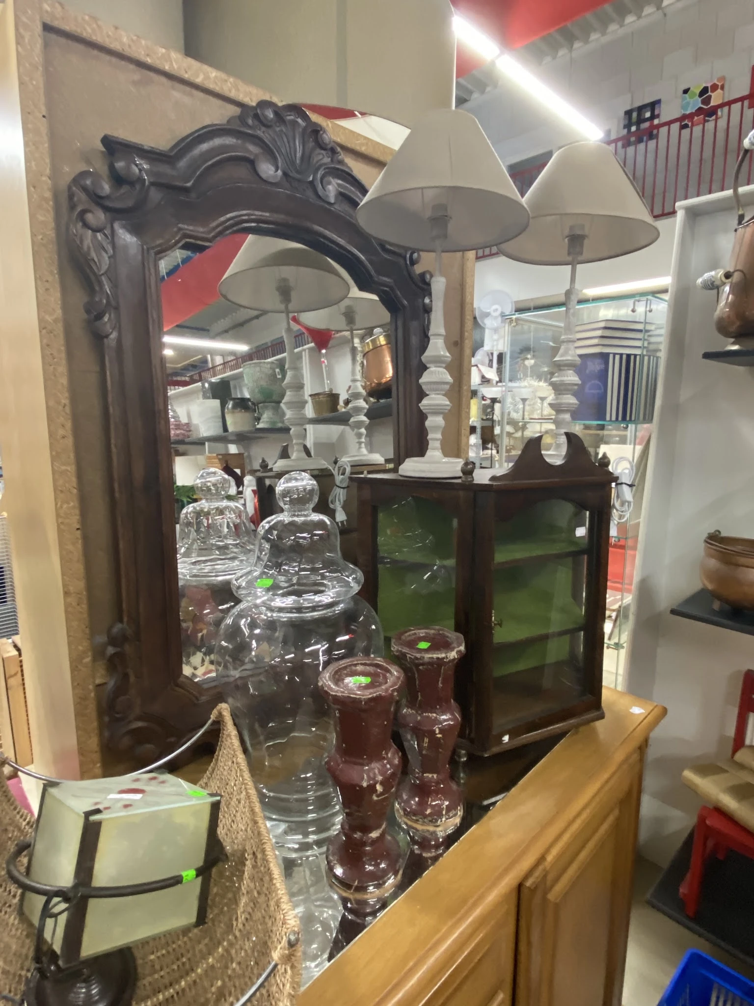 Uitgestalde glazen vazen en kandelaars met witte kaarsenstandaards in de kringloopwinkel