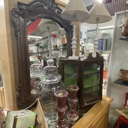 Uitgestalde glazen vazen en kandelaars met witte kaarsenstandaards in de kringloopwinkel