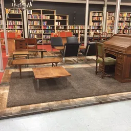 Interieur van kringloopwinkel met vintage meubels, boeken in kastjes, rode vloer en grijs tapijt