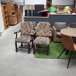 Uitgestalde meubels in de winkel: twee houten stoelen met patroonbekleding en andere zitmeubels op kunstgras.