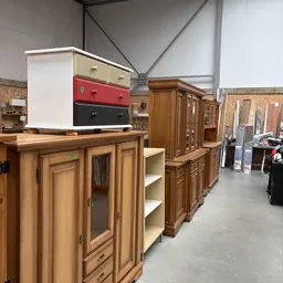 Tweedehands meubels in de winkel: houten kasten en kastenwanden met deuren en laden, waaronder exemplaren met kleurige fronte