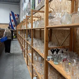 Houten stellingen met glazen serviesgoed, vazen en kristal in een kringloopwinkel