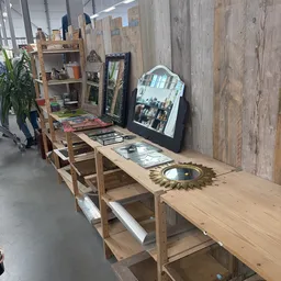 Houten toonbank met spiegels, decoratieve objecten en kunstboeken uitgestald in kringloopwinkel