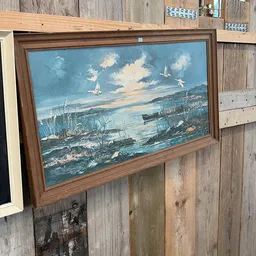 Ingelijst schilderij met zeegezicht, boten en zeilschepen onder bewolkte hemel