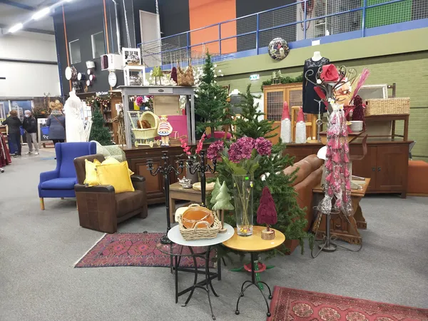 Ingericht interieur met vintage meubels, bloemen in vaas, gele tafel en bruine fauteuils in kringloopwinkel