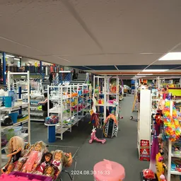 Overzicht van de winkelhal met diverse stellingen vol speelgoed, poppen en kinderspullen langs de zijkanten