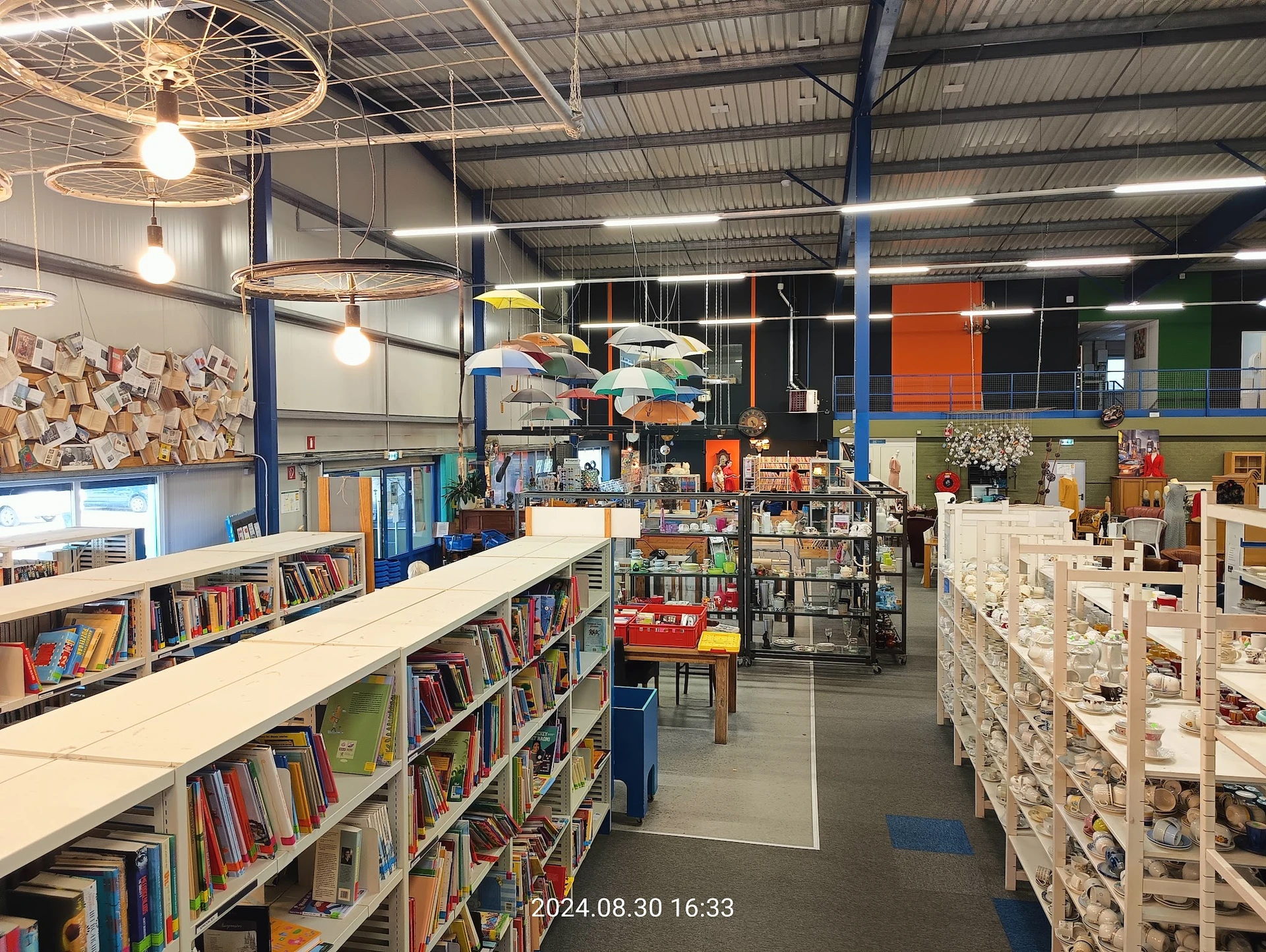 Winkelvloer met boekenrekken, stellingen met spullen en gekleurde wanden in een kringloopwinkel