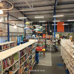 Winkelvloer met boekenrekken, stellingen met spullen en gekleurde wanden in een kringloopwinkel