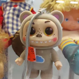 Close-up van een speelgoedbeertje met grote ogen en getande mond, met een grijs oorbandje