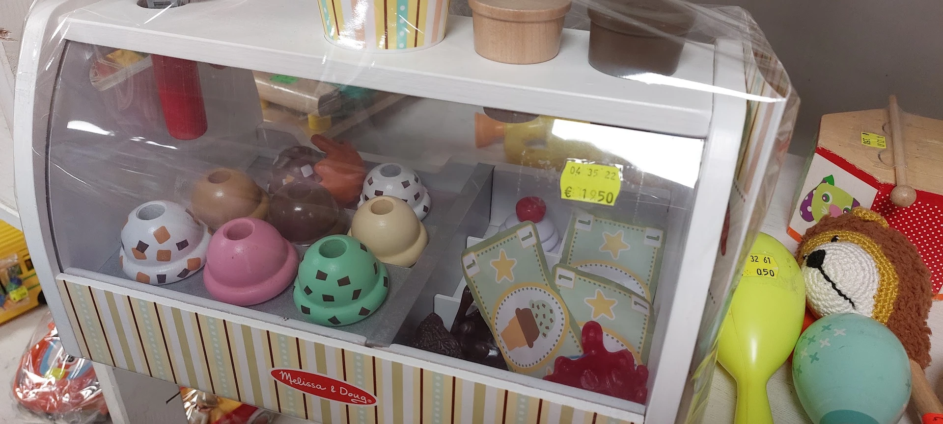 Speelgoedkast met onder meer roze en groene voedersilos, een witte vogel, speelgoedkaarten en rode blokjes.