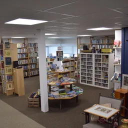 Overzicht van boekenwinkel met boekenrekken, boekentafels en leeshoek met overhead-verlichting