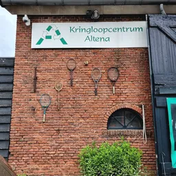 Bakstenen gevel met Kringloopcentrum Altena-logo en decoratieve tennisrackets aan de muur