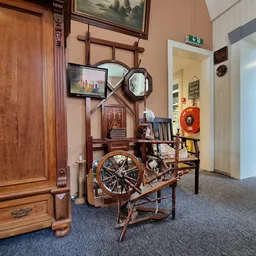 Winkelvloer met diverse tweedehands meubels en decoratie-items, inclusief een fiets, houten deuren en spiegels