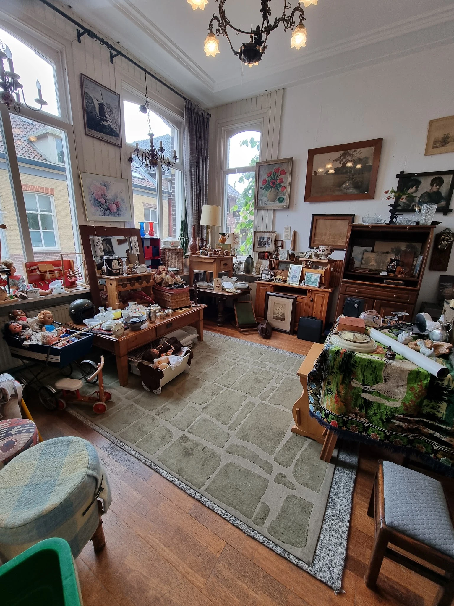 Ruim interieur van kringloopwinkel met houten meubels, vitrines, fotolijsten aan wand en diverse inboedelspullen