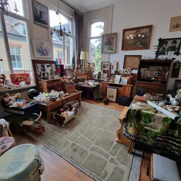 Ruim interieur van kringloopwinkel met houten meubels, vitrines, fotolijsten aan wand en diverse inboedelspullen