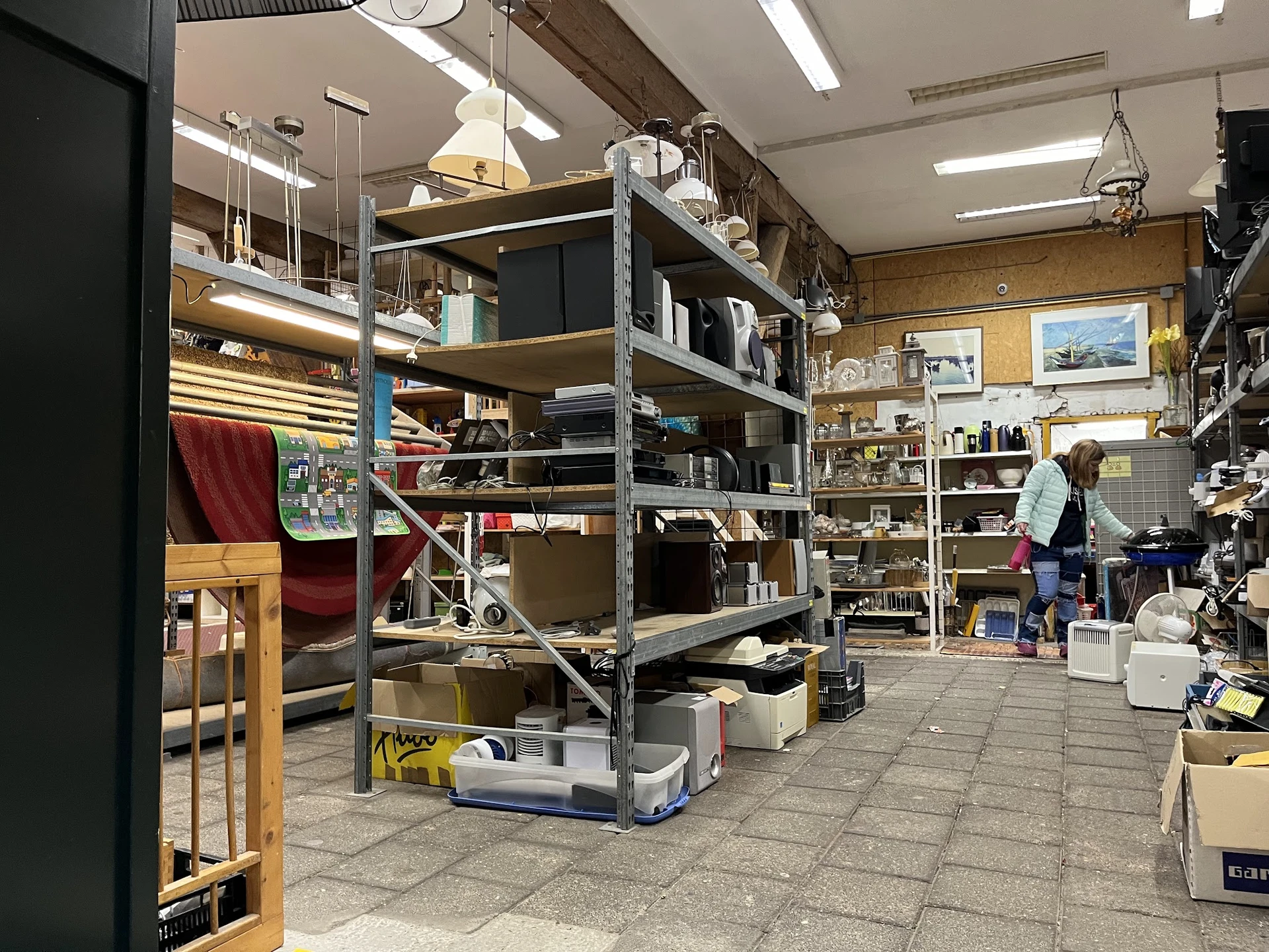 Winkelvloer met metalen stellingen vol met huishoudelijke artikelen en spullen in een kringloopwinkel