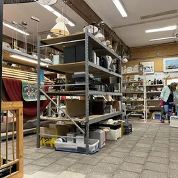 Winkelvloer met metalen stellingen vol met huishoudelijke artikelen en spullen in een kringloopwinkel