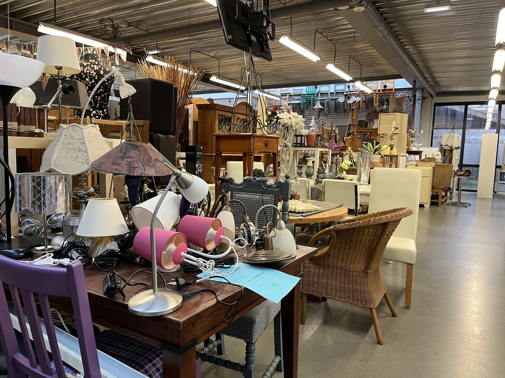 Winkelvloer met uitgestalde meubels, lampen en huishoudartikelen in een ruim magazijn