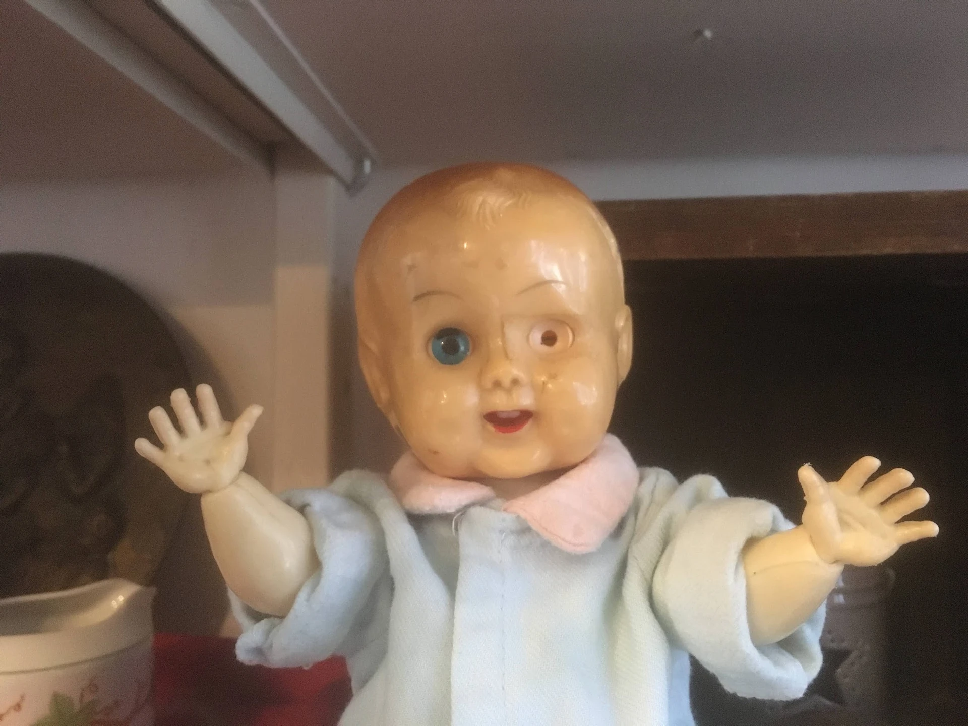 Vintage poppenhoofd met blond haar en blauwe ogen, gekleed in lichtblauw en roze kledingje