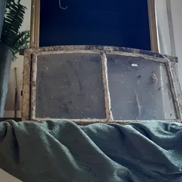 Oud raam met twee ruiten in houten frame, gedeeltelijk bedekt met stof