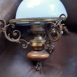 Decoratieve bronzen schaal met ornamentale handvatten en houten voet, close-up.