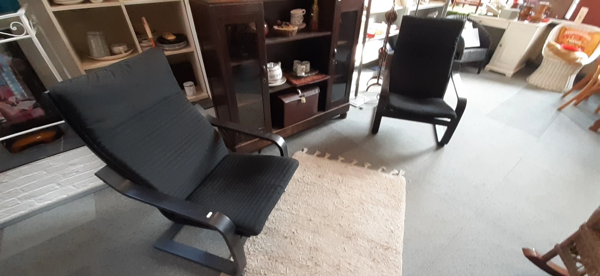 Tweedehands meubels: zwarte stoelen en donkerbruine kasten in de winkelruimte