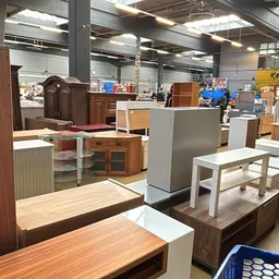 Verschillende meubels in de winkel, waaronder kasten, tafels en banken in diverse kleuren en stijlen