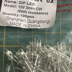 Close-up van ongeveer 100 elektronische componenten (mogelijk weerstanden of diodes) in een doosje met geel raster.