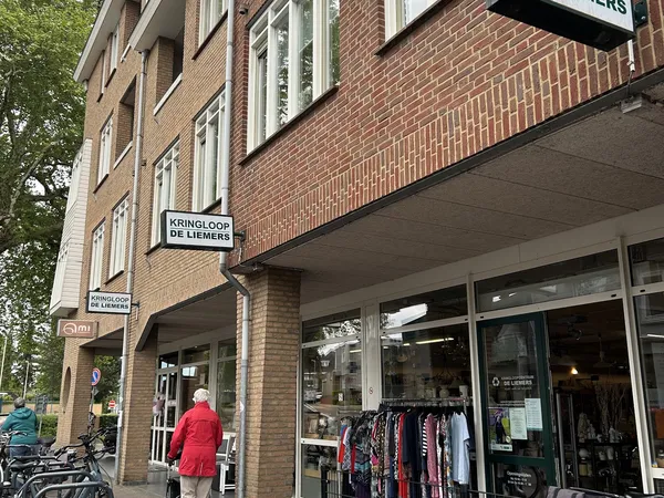 Gevel van kringloopwinkel De Liemers met uitstalde kleding in de etalage en straatnaam zichtbaar