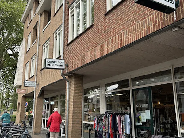 Voorgevel van kringloopwinkel met grote ramen, winkelnaam op bord, tweedehands kleding zichtbaar in etalage