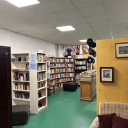 Boekenkasten en boekenrekken in een kringloopwinkel met groene vloer en gele muur
