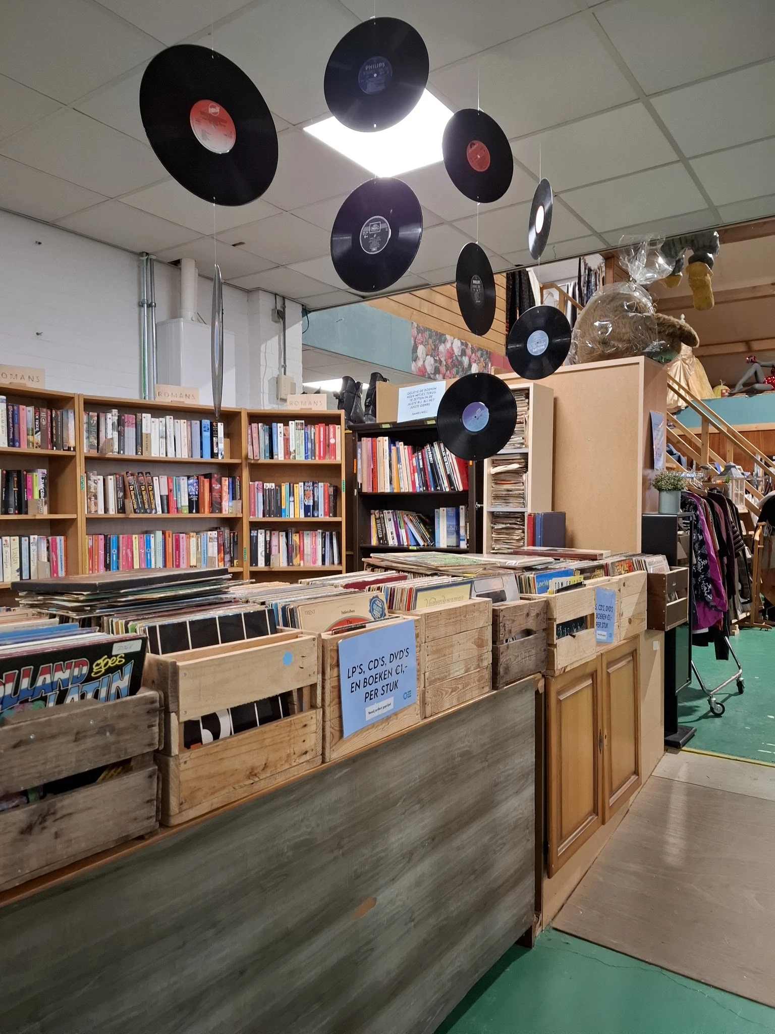 Winkelinterieur met boekenrekken, houten kasten met tweedehands spullen en vinyl platen als decoratie