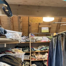 Stellingen met tweedehands kleding en textiel in verschillende kleuren en types, opgehangen en opgestapeld