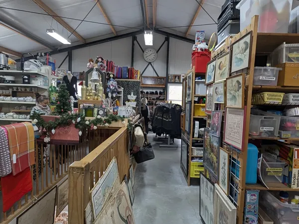 Winkelvloer van kringloopwinkel met stellingen, spullen en diverse tweedehands artikelen langs de muren