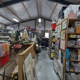 Winkelvloer van kringloopwinkel met stellingen, spullen en diverse tweedehands artikelen langs de muren