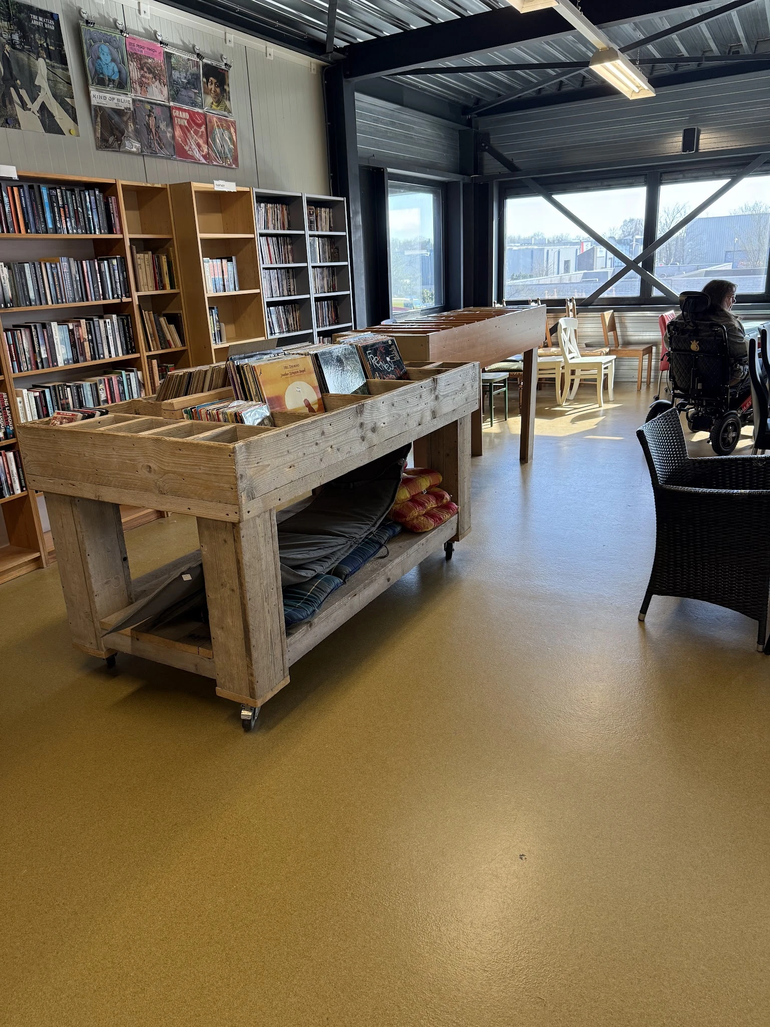 Winkelvloer met houten toonbank, boekenkasten, zithoeken en grote ramen met uitzicht op de stad
