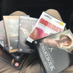 Verzameling dvd's en blu-rays in een doos, waaronder films als 'Alexander', 'Forrest Gump' en 'Warcraft'