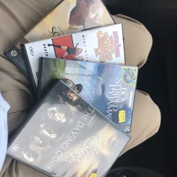 Stapel dvd's en blu-ray films op een stoel, waaronder titels zoals Game of Thrones en Scary Movie
