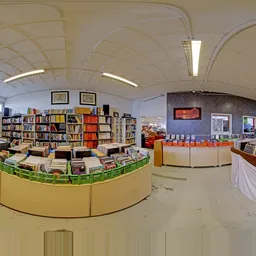 Overzicht van de winkelruimte met boekenrekken, gele balieks, oranje boekenkast en verlichte plafondpanelen