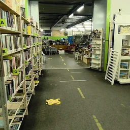 Winkelvloer met boekenrekken links, diverse spullen en meubels, gele markeringen op de grond