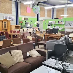 Winkelvloer met bruine en grijze fauteuils en zitmeubels, groene wand op achtergrond, diverse meubels en huishoudartikelen